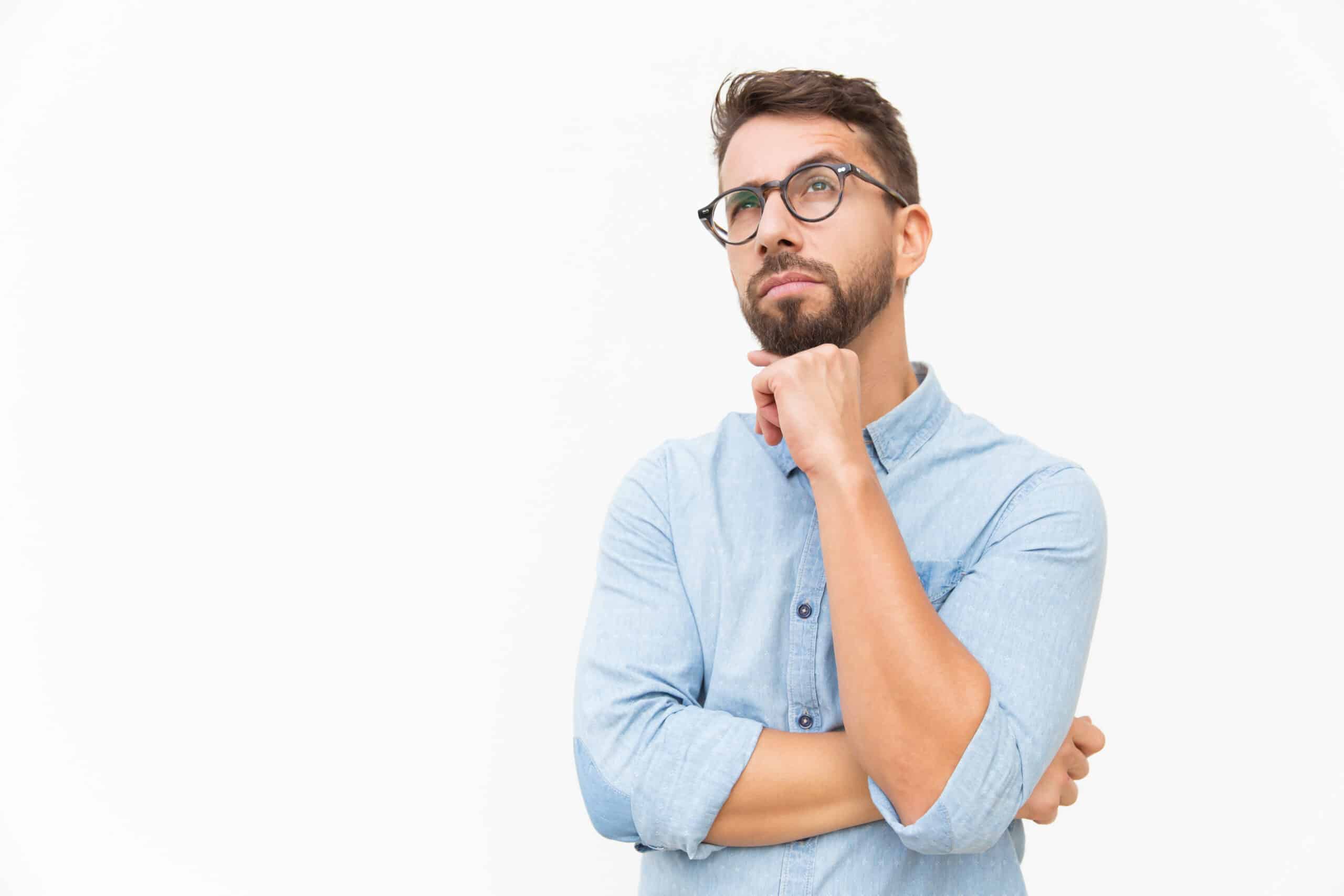 Pensive customer thinking over special offer Pensive customer thinking over special offer, touching chin, looking up. Handsome young man in casual shirt and glasses standing isolated over white background. Advertising concept